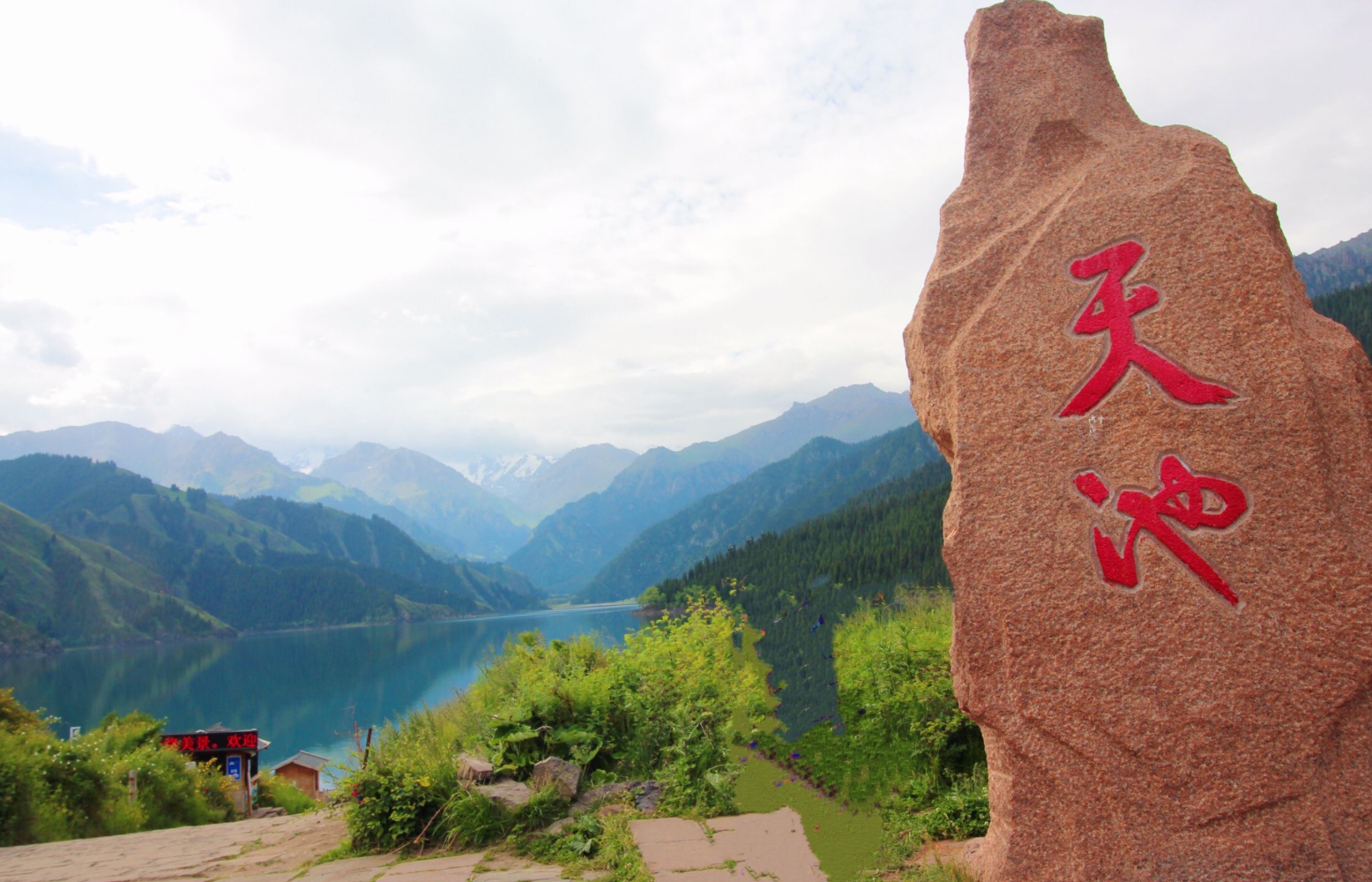 Calm alpine lake ringed by forested mountains in Xinjiang's Tianshan range
