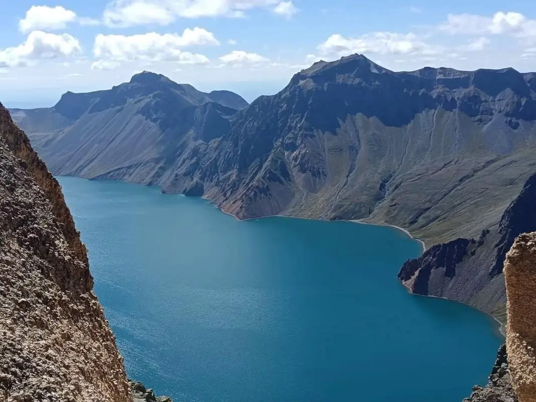 Heavenly Lake Tianchi with partially thawed water beneath snow-dusted peaks near Urumqi