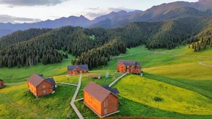 Kazakh yurts on the Mulei grassland with the spruce hills behind
